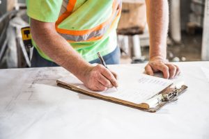 Construction worker writing on a piece of paper onsite